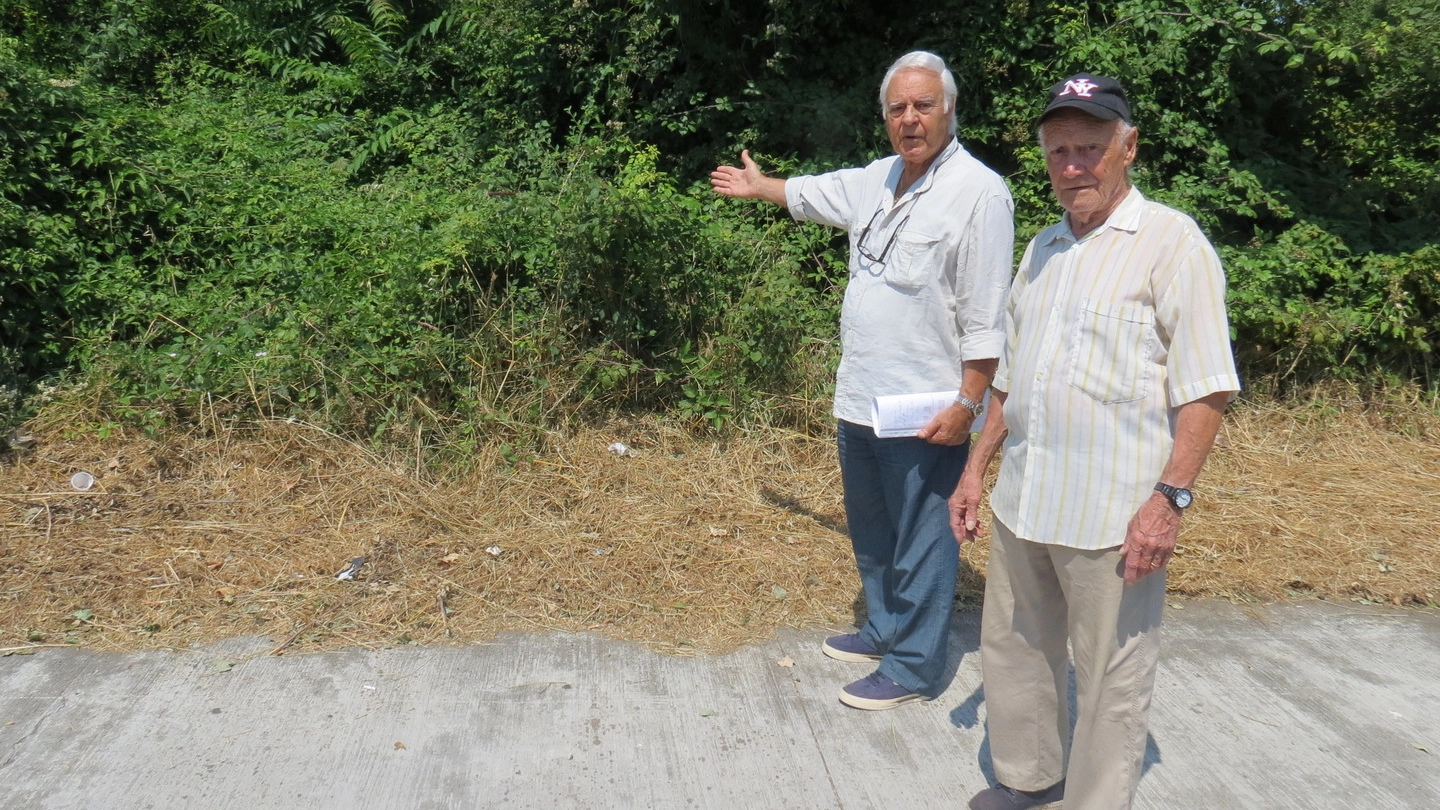 Due residenti della zona indicano il luogo dove dovrebbe sorgere la strada di collegamento per le abitazioni