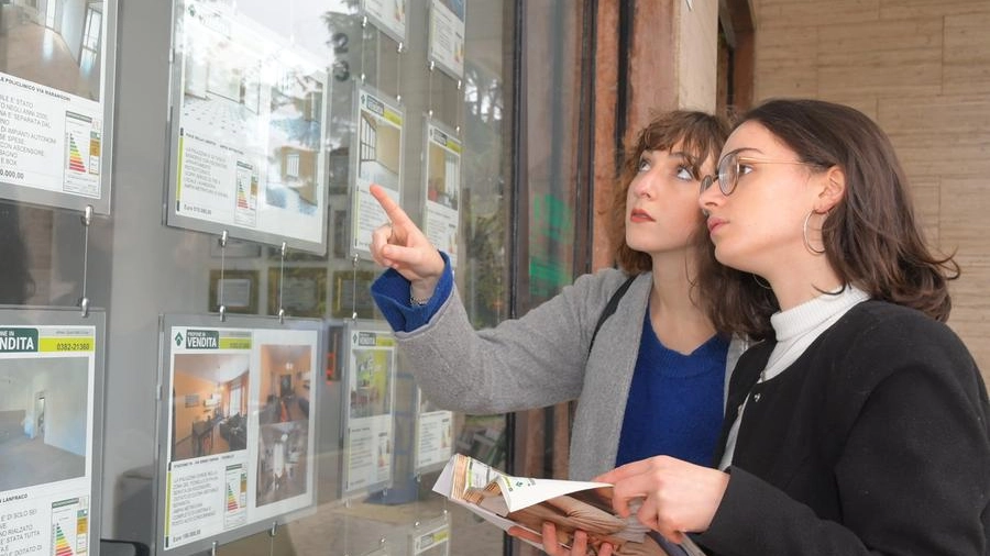 Due giovani si soffermano davanti alla vetrina di un’agenzia immobiliare