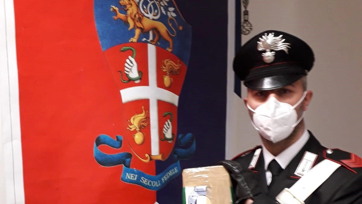 Un carabiniere mostra il pacco con la droga sequestrata