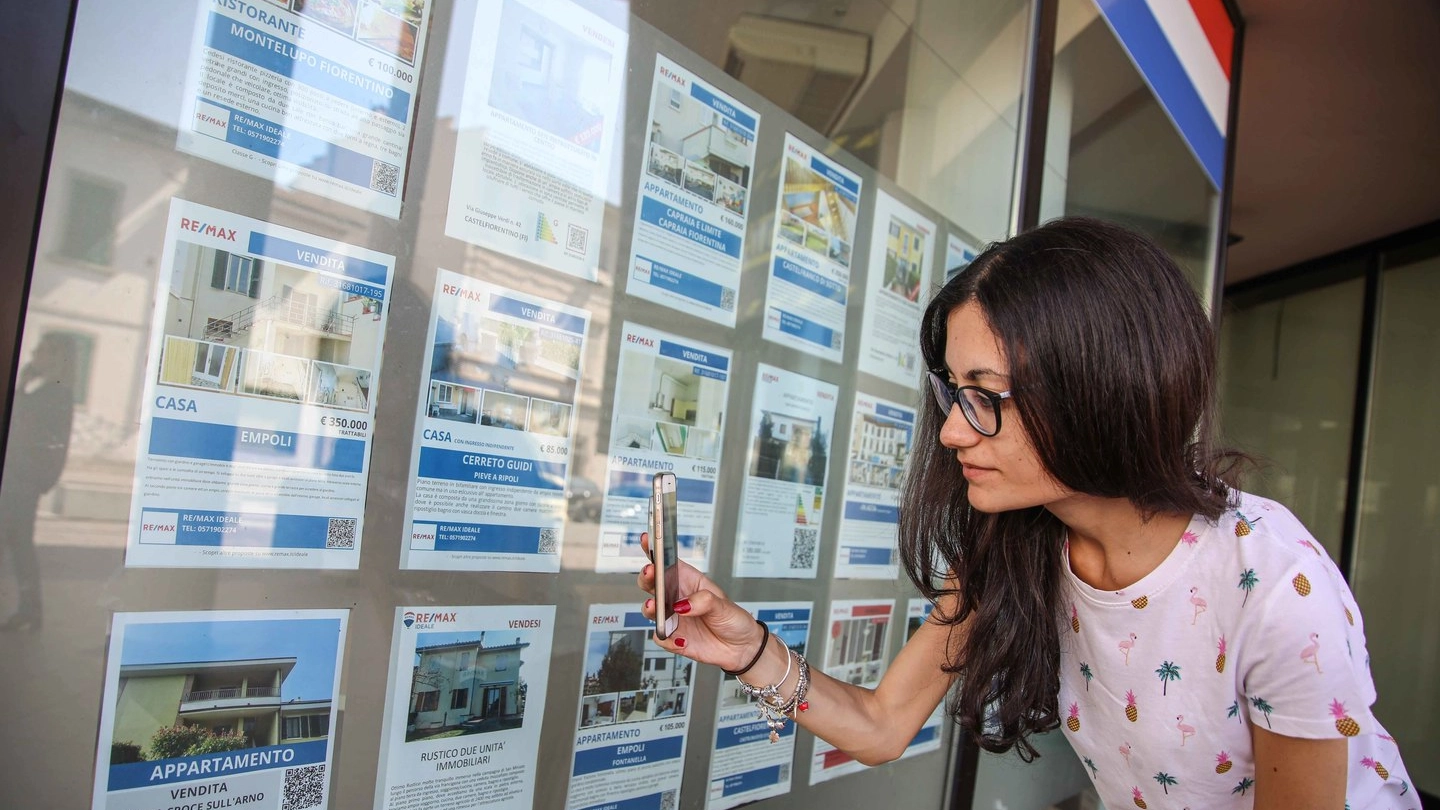 Una cliente davanti agli avvisi di un'agenzia immobiliare (foto di repertorio)