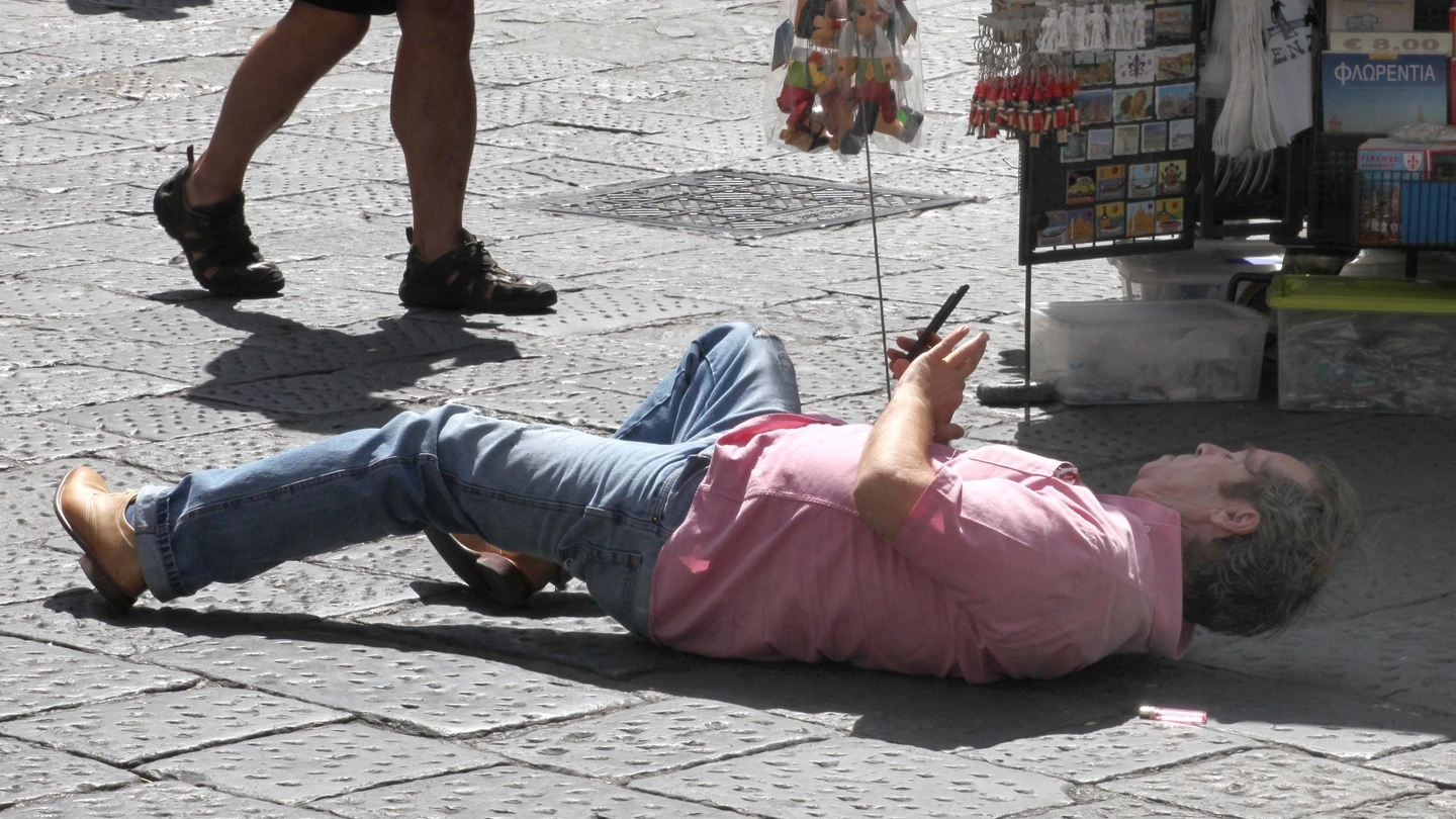 Un turista si sdraia in piazza per fotografare il Duomo di Firenze (New Press Photo)