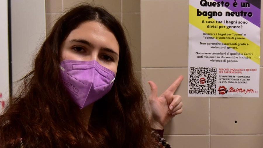 Una giovane mostra un cartello che indica un bagno 'neutro'