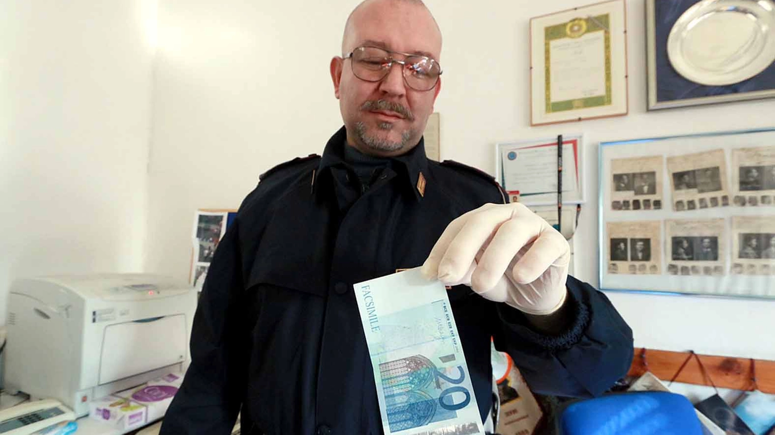 Un poliziotto mostra le banconote fasulle. Foto Gianni Nucci/Germogli