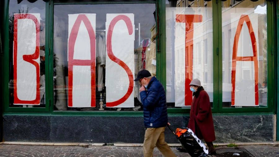 La grande scritta 'Basta' sulla vetrina di un  negozio chiuso (Ansa)