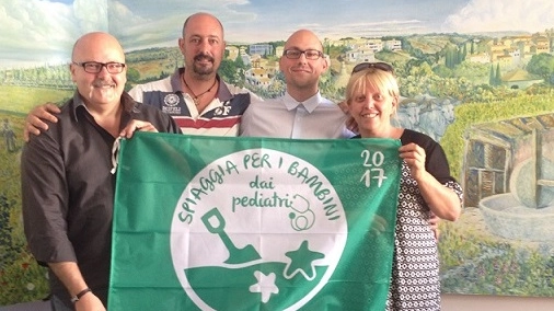 Il sindaco di Bibbona Massimo Fedeli (a sinistra) mostra orgoglio la Bandiera Verde