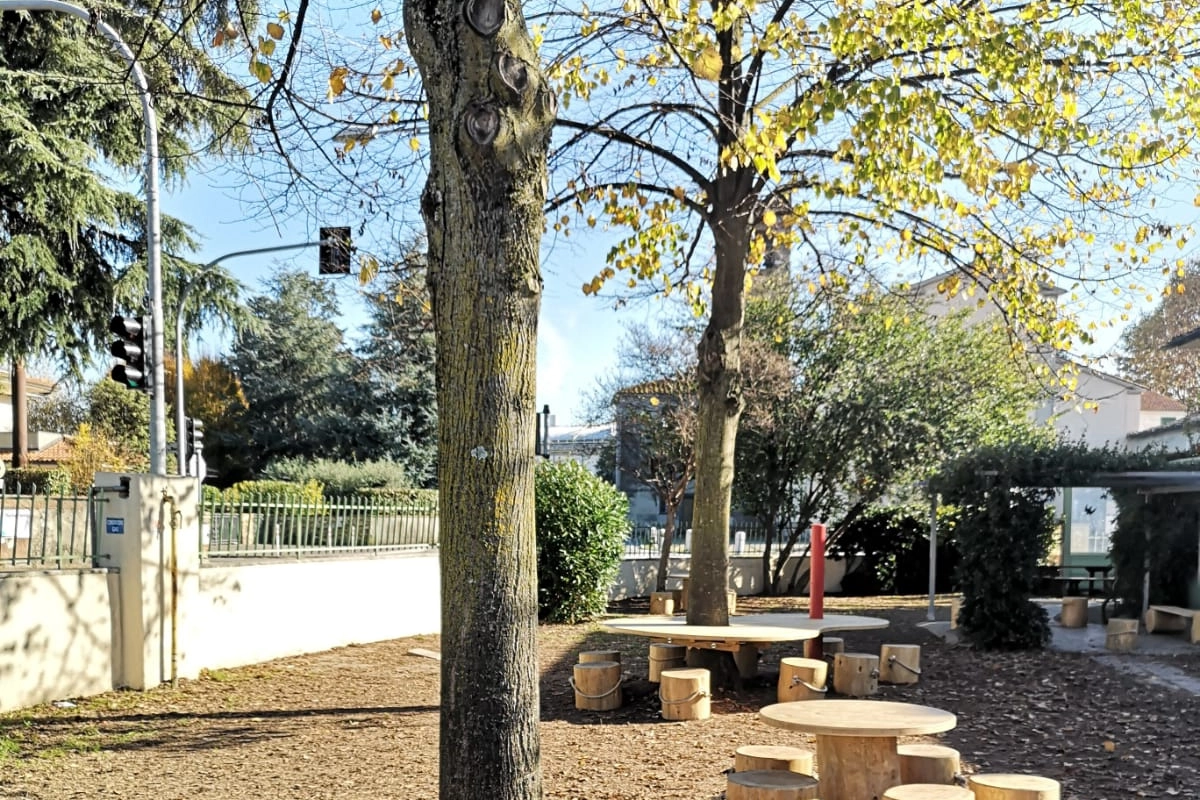 Sedute in materiale naturale nel giardino di un plesso 