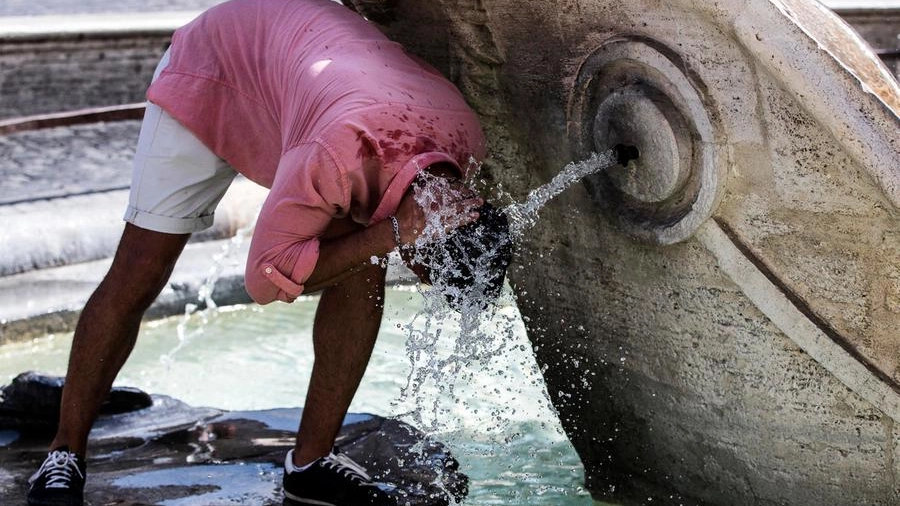 Turisti si rinfrescano per il caldo nella fontana di piazza di Spagna (Ansa)