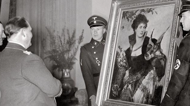 Adolf Hitler mentre ammira un dipinto sostenuto da due soldati nazisti