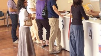 Alcuni cittadini mentre fanno la fila per poter depositare soldi sui propri conti correnti in un ufficio postale