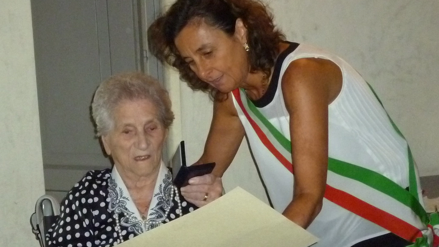 Elide Venturini riceve dalle mani del presidente del consiglio comunale, Ilaria Santi, il gigliato d’argento per i 100 anni raggiunti