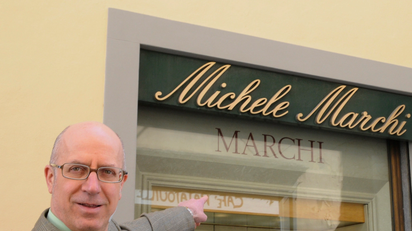 Angelo Marchi indica l’ingresso del suo negozio (foto Alcide)
