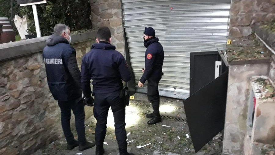 I carabinieri di fronte all'ingresso del locale danneggiato dall'ordigno  