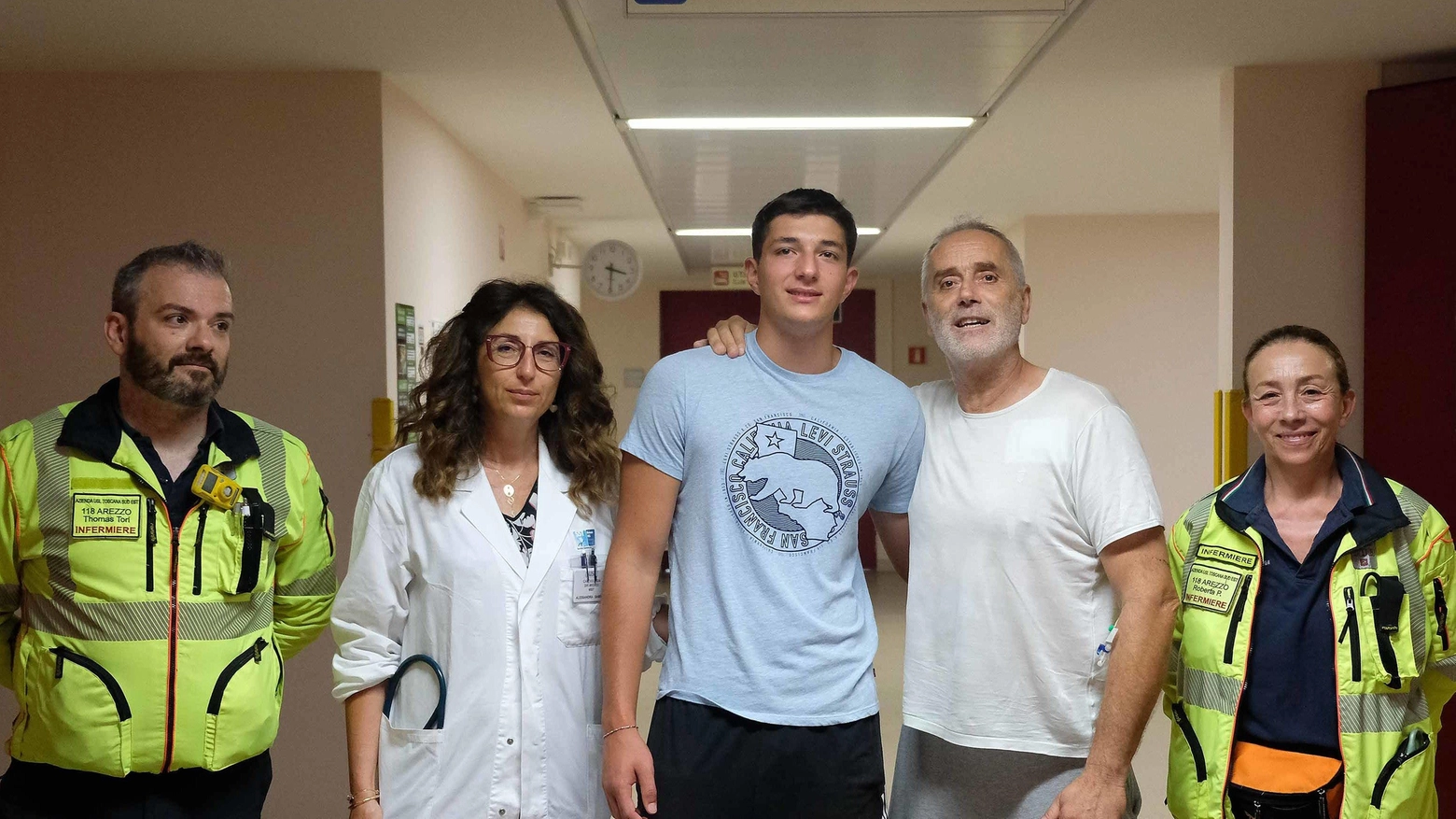Alessandro, in maglia celeste, con l'uomo salvato, in t shirt bianca. Con loro i medici del 118 e la vice del reparto, la dottoressa Anna Sabini