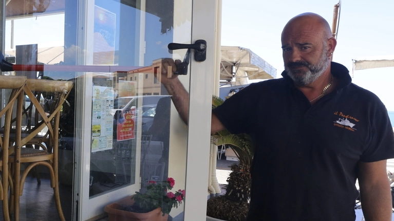 Fabrizio Fiorini, titolare de "Il Peschereccio", mostra la porta forzata dai ladri 
