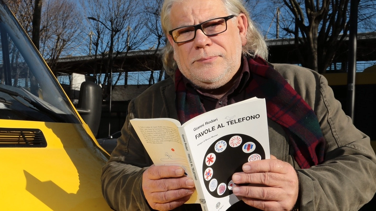 Bruno Magnolfi, 60 anni, appoggiato alla scuolabus  con in mano  il libro «Favole al telefono» di Gianni Rodari