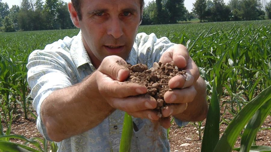Un agricoltore mostra la terra arida del periodo a causa della prolungata siccità
