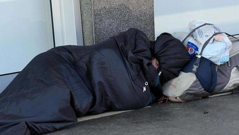 Un senzatetto dorme su un marciapiede