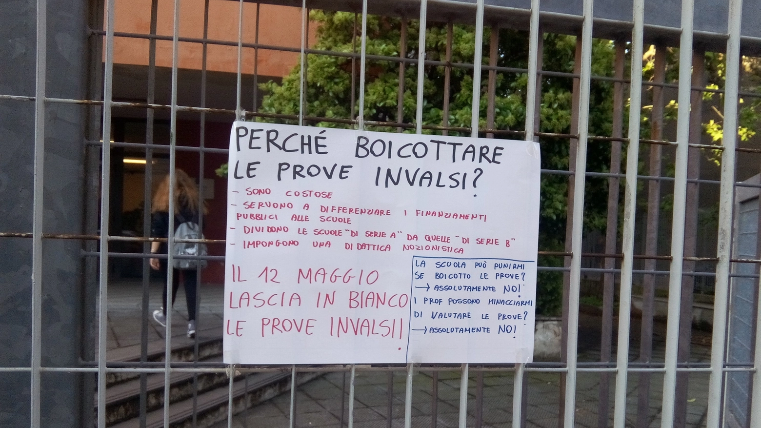Un cartello affisso su una scuola a Prato
