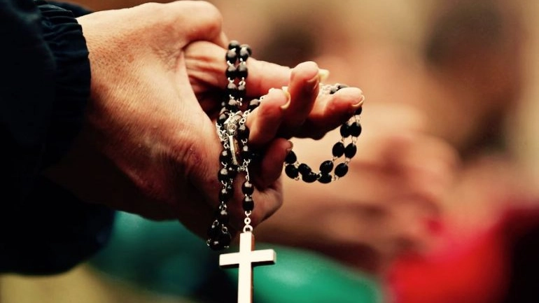 Un rosario tra le mani in preghiera