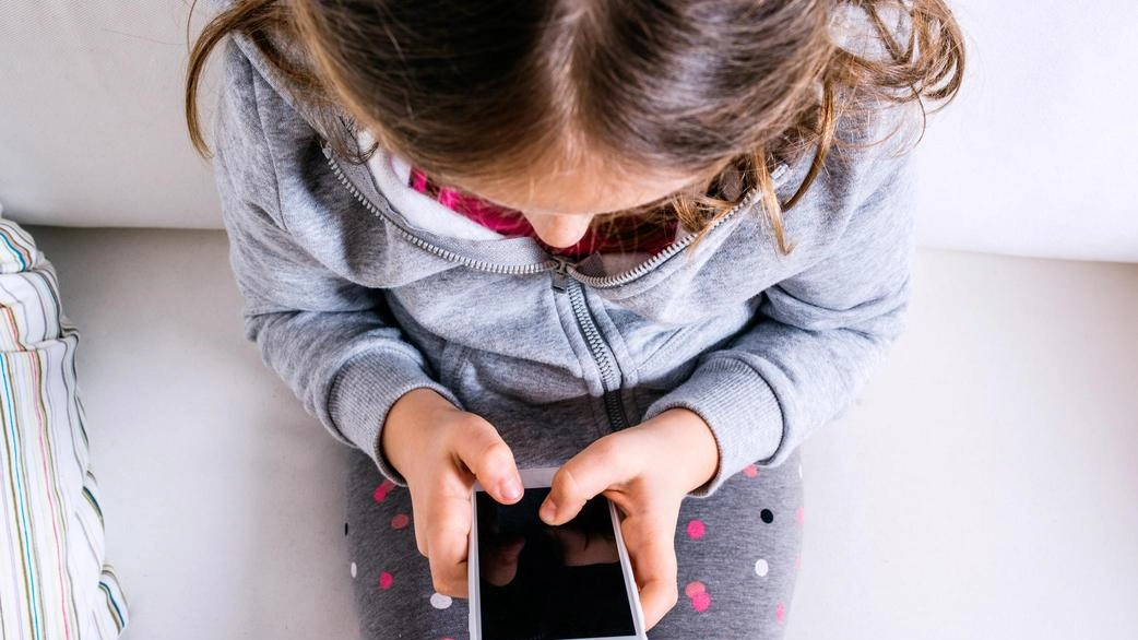 Una ragazzina con lo smartphone seduta sul divano: sono tanti i pericoli legati al mondo di internet e della rete Una ragazzina con lo smartphone seduta sul divano: sono tanti i pericoli legati al mondo di internet e della rete