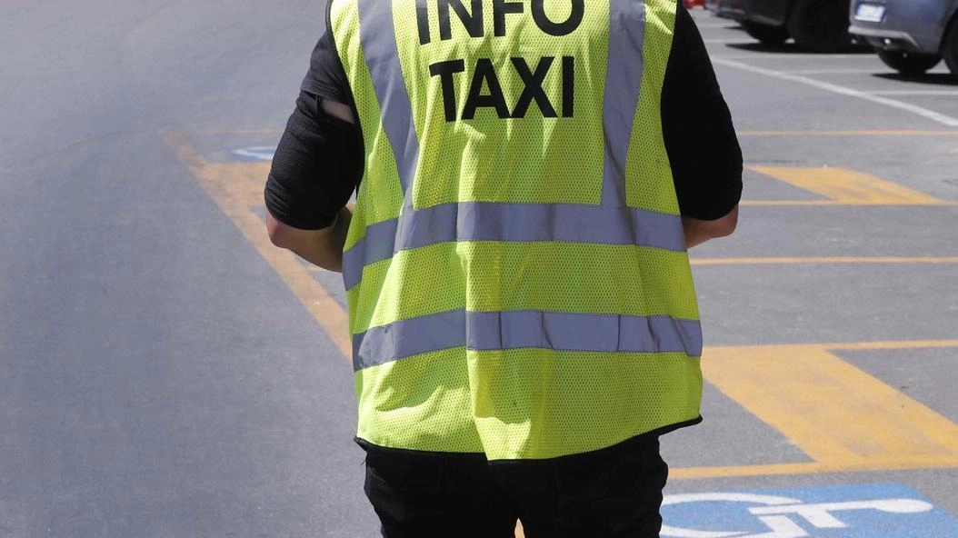 Lo steward alla stazione, sullo sfondo i taxi semi-nascosti nell’angolo della piazza Lo steward alla stazione, sullo sfondo i taxi semi-nascosti nell’angolo della piazza