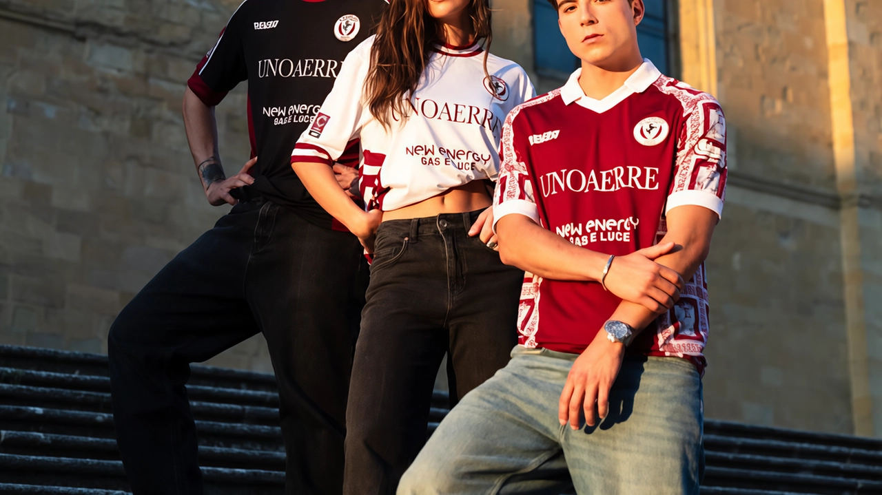 Due modelli e una modella con le maglie dell’Arezzo calcio. Sulla spalla della maglia amaranto il simbolo della Madonna del Conforto Due modelli e una modella con le maglie dell’Arezzo calcio. Sulla spalla della maglia amaranto il simbolo della Madonna del Conforto