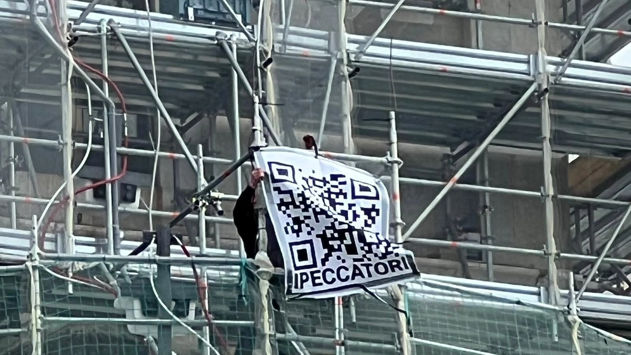 La bandiera appesa al ponteggio, mentre viene rimossa la mattina seguente