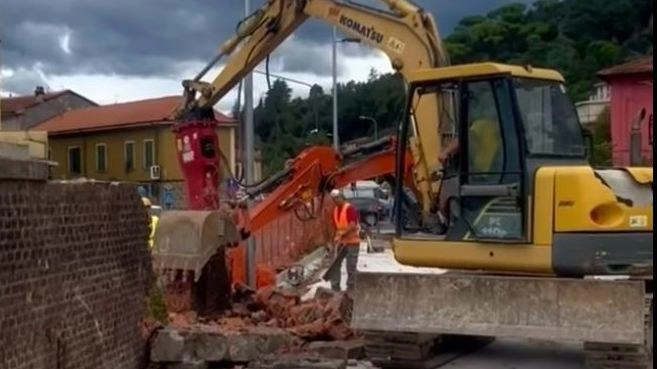 La ruspa al lavoro per abbattere il vecchio muro lungo la linea ferroviaria dismessa La ruspa al lavoro per abbattere il vecchio muro lungo la linea ferroviaria dismessa