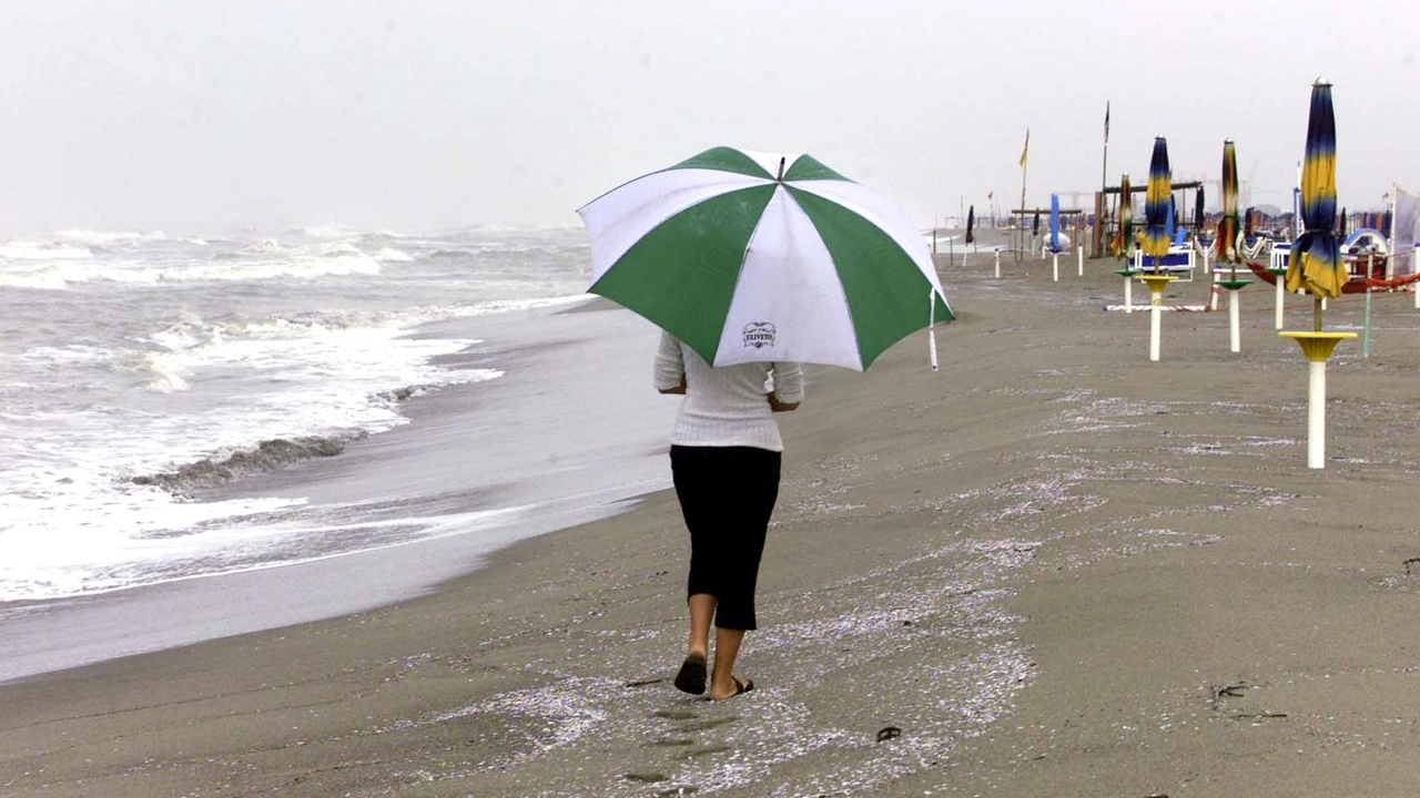 Con l'ombrello in spiaggia aspettando l'estate (Ansa)