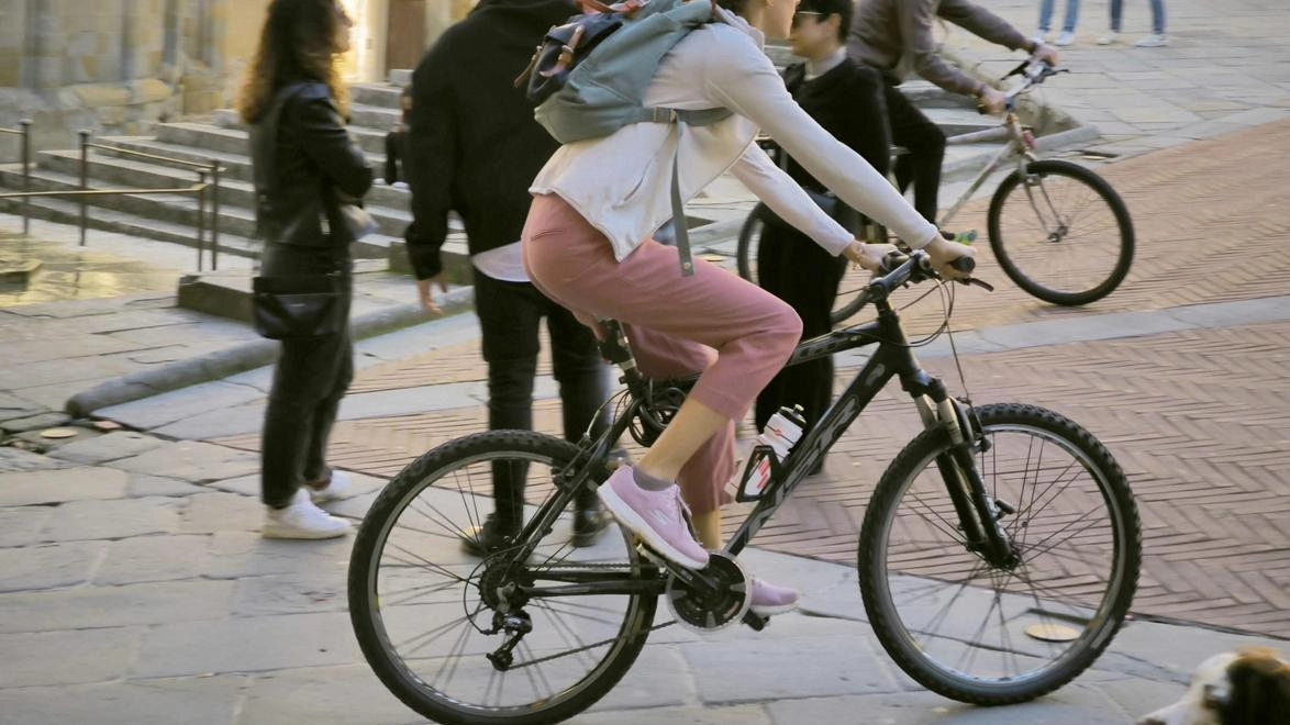 Turisti in sella alle bici attraversano Piazza Grande, nel cuore della città