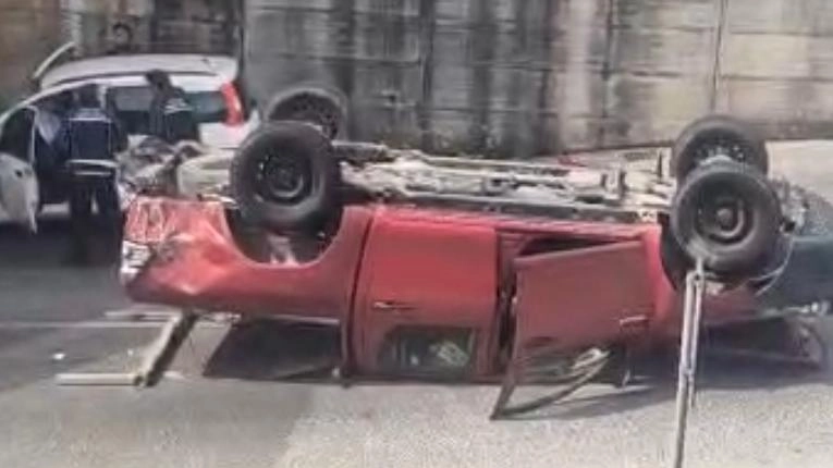 Il pick-up ribaltato dopo essere stato travolto dall’auto che procedeva contromano e sullo sfondo la Polizia municipale mentre esegue i rilievi del caso