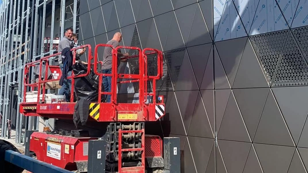 Gli operai intenti a montare i pannelli della copertura esterna della tribuna Gli operai intenti a montare i pannelli della copertura esterna della tribuna