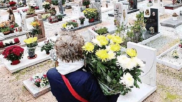 Una signora visita i propri parenti defunti in un cimitero Una signora visita i propri parenti defunti in un cimitero