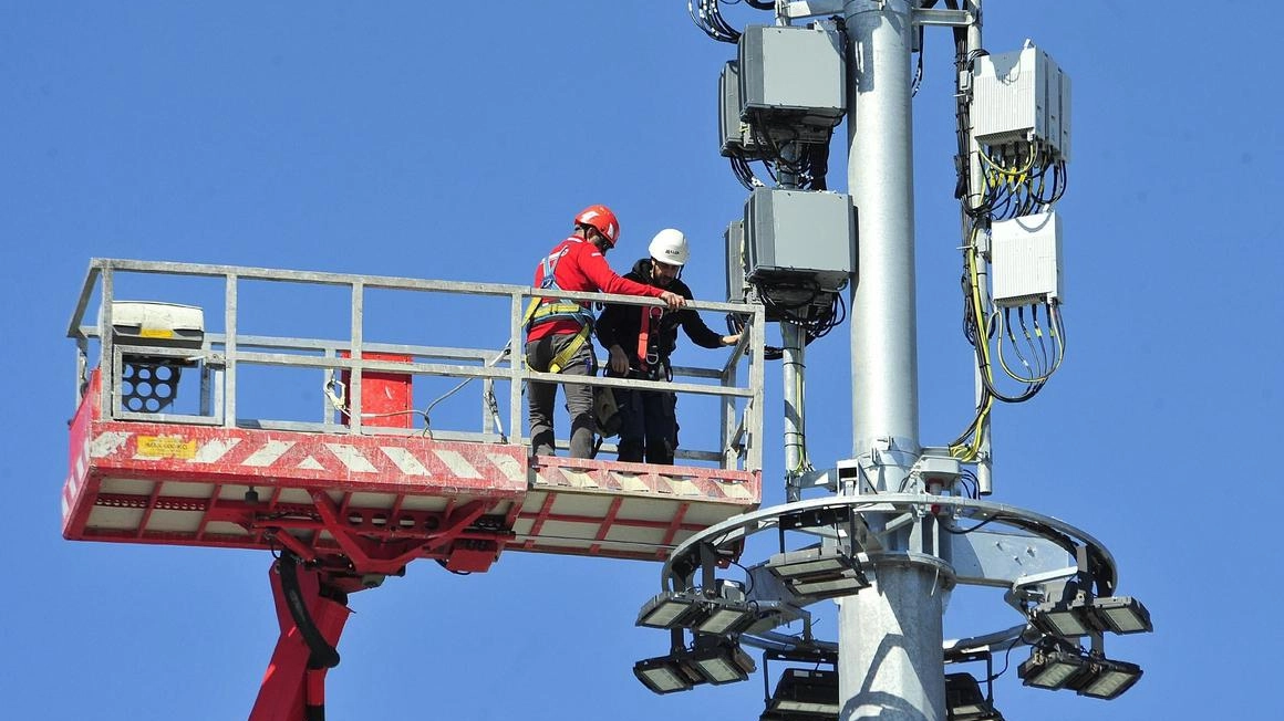 Operai impegnati su una gru per il completamento delle operazioni di installzione di una maxi antenna di telefonia Operai impegnati su una gru per il completamento delle operazioni di installzione di una maxi antenna di telefonia
