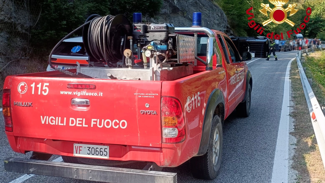 L'intervento dei vigili del fuoco e, sullo sfondo, l'auto ribaltata