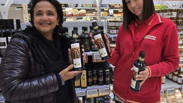 Rita Guastella all’interno di uno dei market Conad mostra le bottiglie del prodotto dell’azienda che conduce con il marito Giuseppe