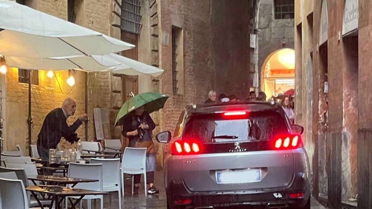 Un’auto all’Arco dei Rossi, pronta a sbucare in Banchi di Sopra, passando accanto ai tavolini Un’auto all’Arco dei Rossi, pronta a sbucare in Banchi di Sopra, passando accanto ai tavolini