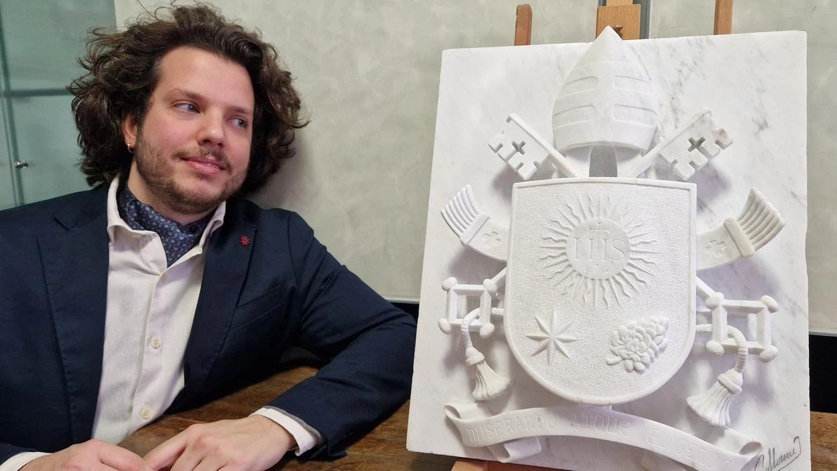 Filippo Gallorini accanto alla sua opera: lo stemma papale in bassorilievo che ha dedicato a Papa Francesco