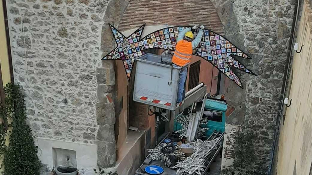 Un momento dell’installazione della Cometa fatta all’uncinetto e. sistemata sopra la Porta Senese all’ingresso del centro storico Un momento dell’installazione della Cometa fatta all’uncinetto e. sistemata sopra la Porta Senese all’ingresso del centro storico