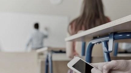 Uno studente mentre chat sui social network di nascosto dall’insegnante durante una lezione Uno studente mentre chat sui social network di nascosto dall’insegnante durante una lezione