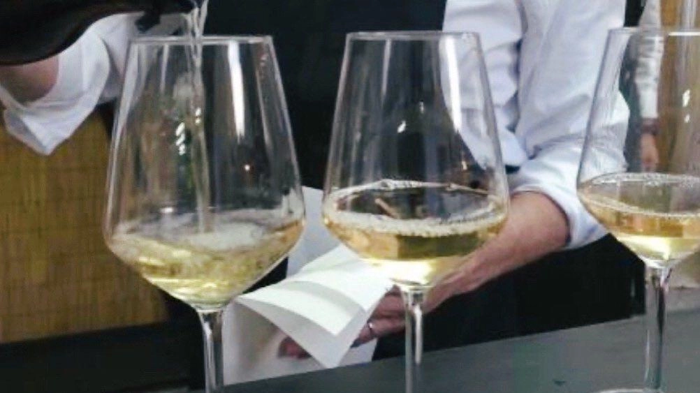 Un sommelier riempie i calici a due avventoni a una passata edizione della festa del vino a Montecarlo Un sommelier riempie i calici a due avventoni a una passata edizione della festa del vino a Montecarlo
