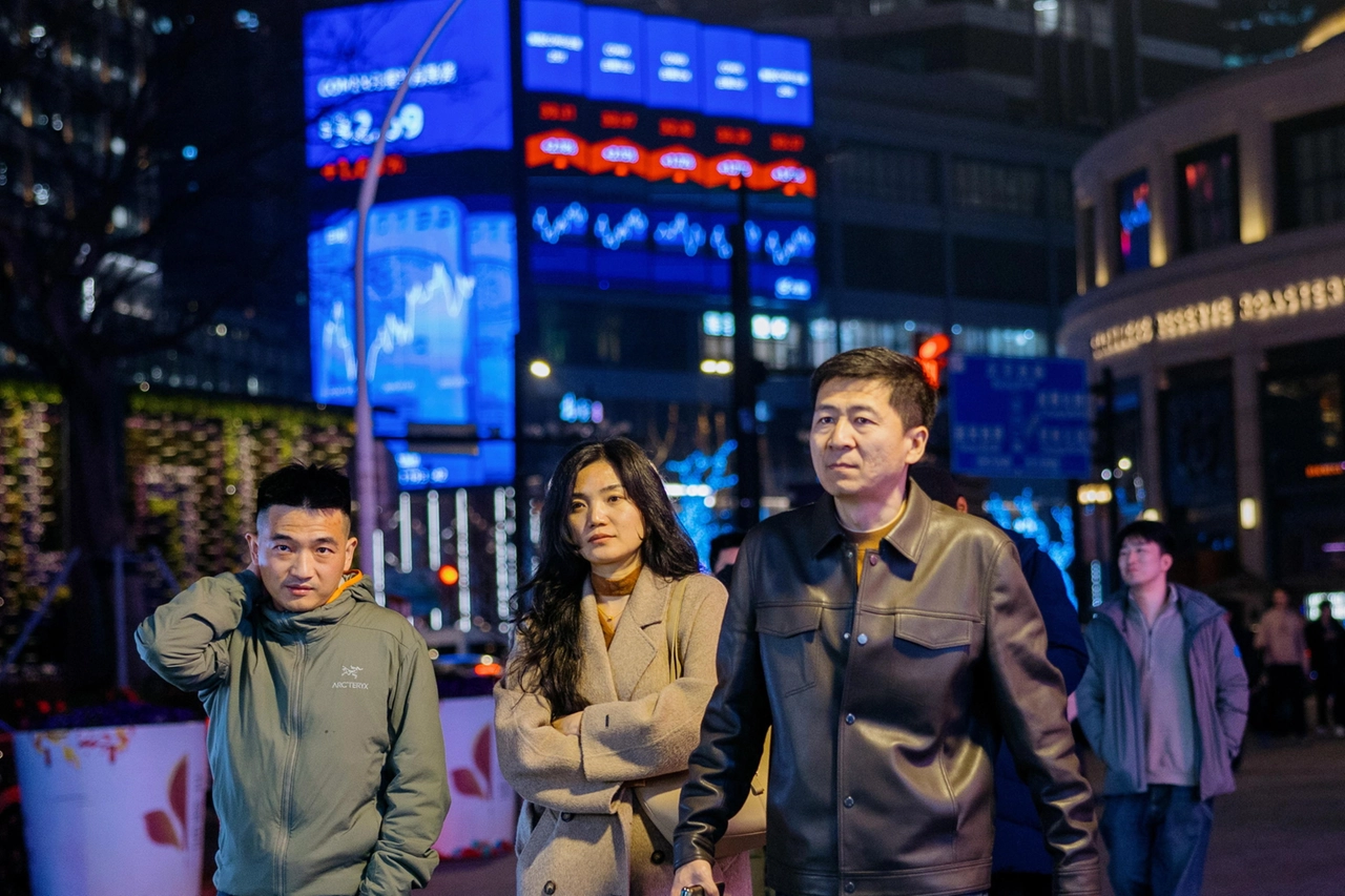 Shanghai, gente cammina davanti a un megaschermo con le ultime notizie di Borsa (Ansa)