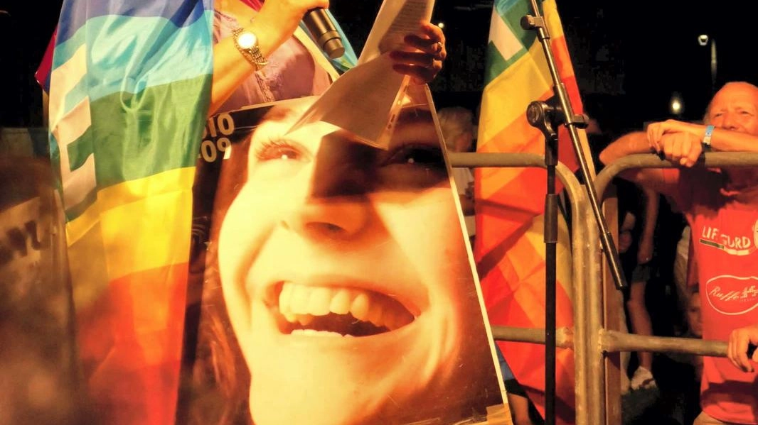 Daniela Rombi con la gigantografia della figlia Emanuela morta a 21 anni e con la bandiera arcobaleno al collo. Oltre a verità giustizia e sicurezza, appello anche per la pace