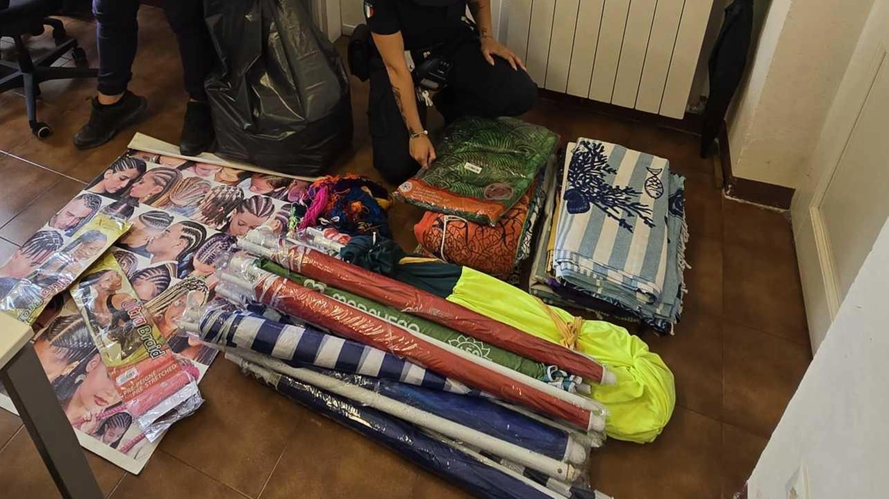 Una agente della polizia locale di Levanto impegnata nell’inventario della merce sequestrata ieri lungo il litorale: ombrelloni, teli da mare e materiale per collanine