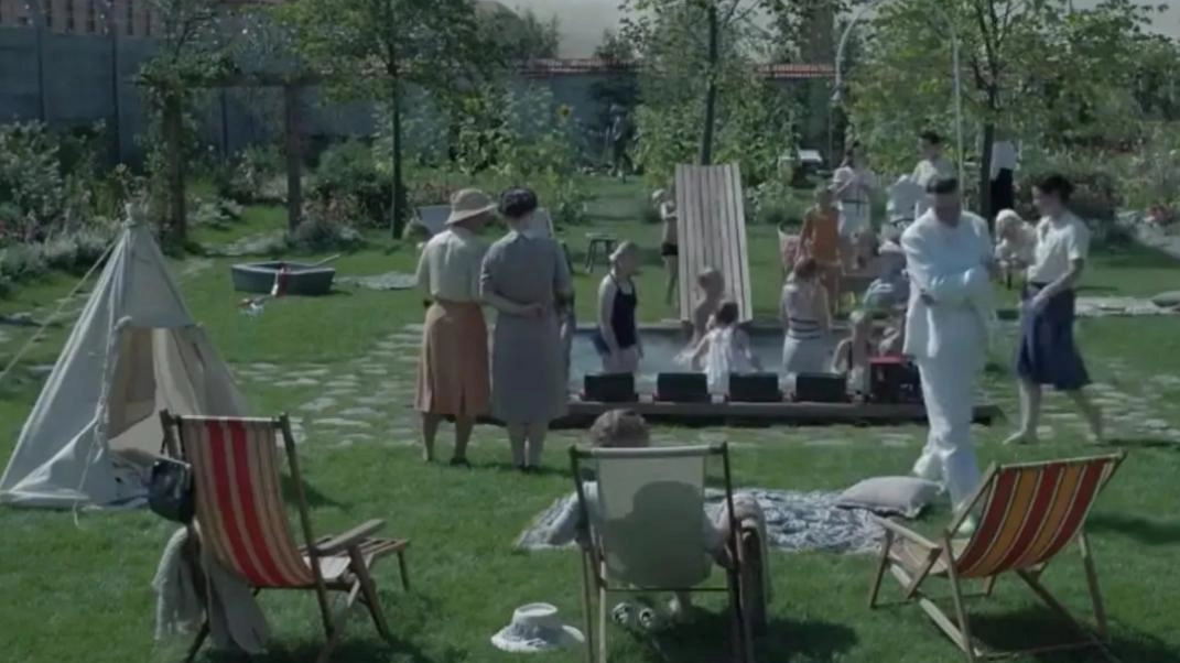 Una scena de La zona d’interesse: una festa nella villa del capo di Auschwitz con il campo di concentramento accanto Una scena de La zona d’interesse: una festa nella villa del capo di Auschwitz con il campo di concentramento accanto