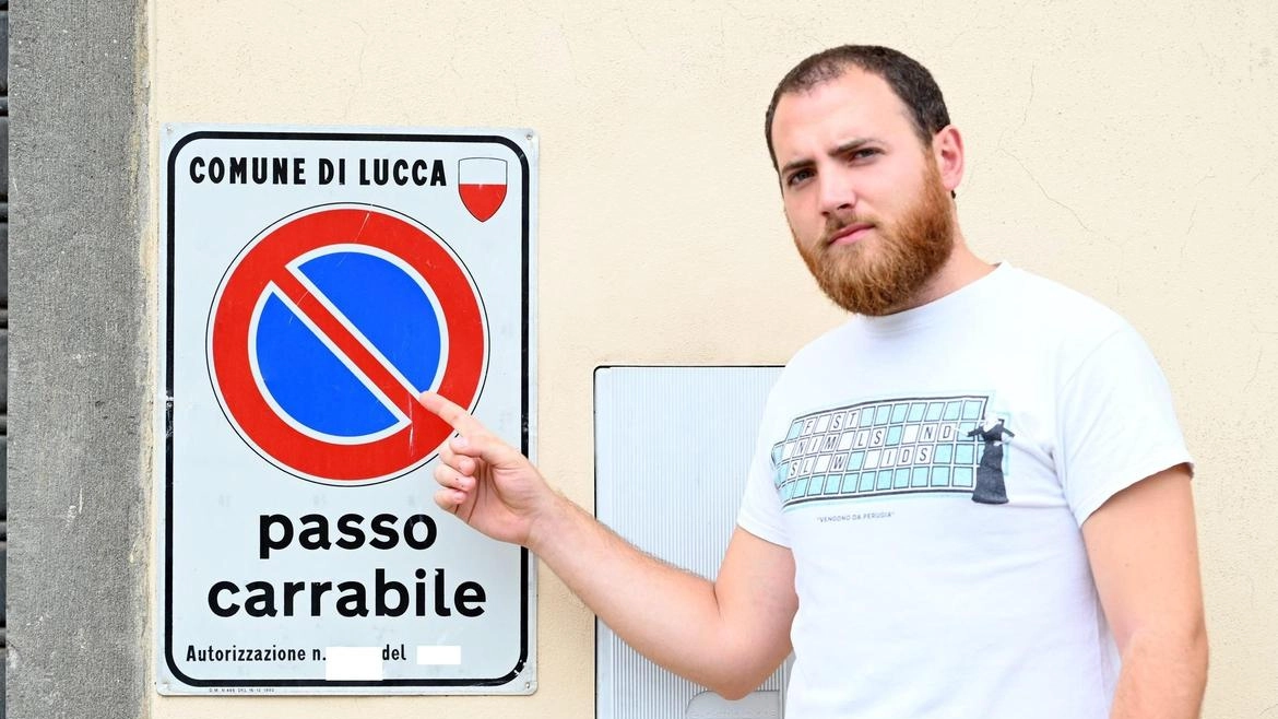 Un ragazzo mostra un cartello di un passo carrabile (foto Alcide) Un ragazzo mostra un cartello di un passo carrabile (foto Alcide)