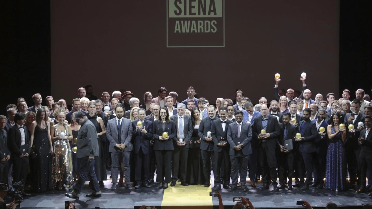 Il consueto scatto finale sul palco del Teatro dei Rinnovati: fotografi provenienti da tutto il mondo condividono la gioia per i riconoscimenti ricevuti Il consueto scatto finale sul palco del Teatro dei Rinnovati: fotografi provenienti da tutto il mondo condividono la gioia per i riconoscimenti ricevuti