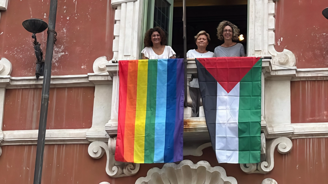 La bandiera palestinese e quella della pace esposte sulla facciata di Palazzo Ducale, sede della Provincia