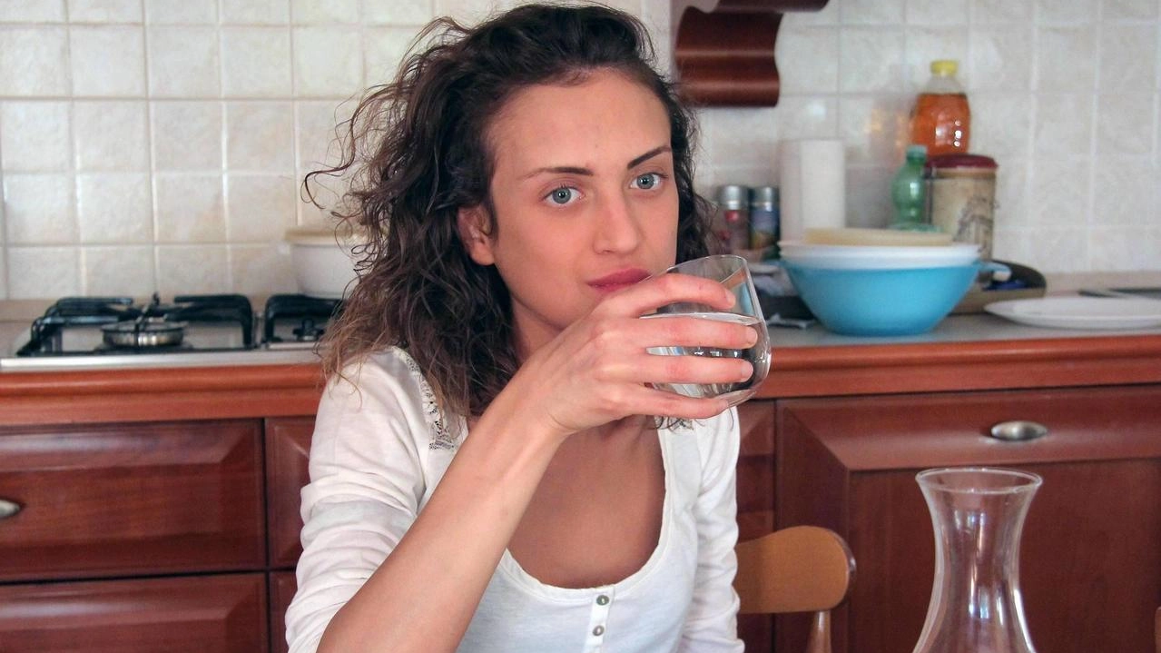 Una ragazza beve un bicchiere di acqua (foto archivio) Una ragazza beve un bicchiere di acqua (foto archivio)