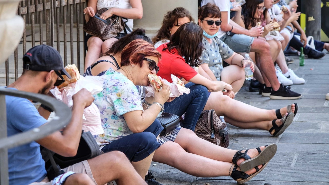 Turisti mangiano panini seduti in centro a Firenze